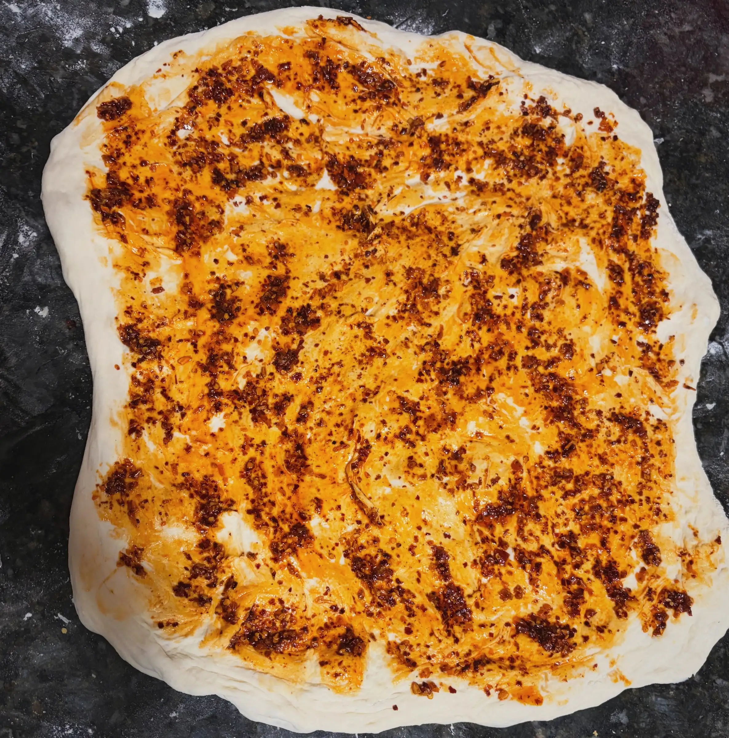 Sourdough dough spread with chili oil and pepper jack before rolling