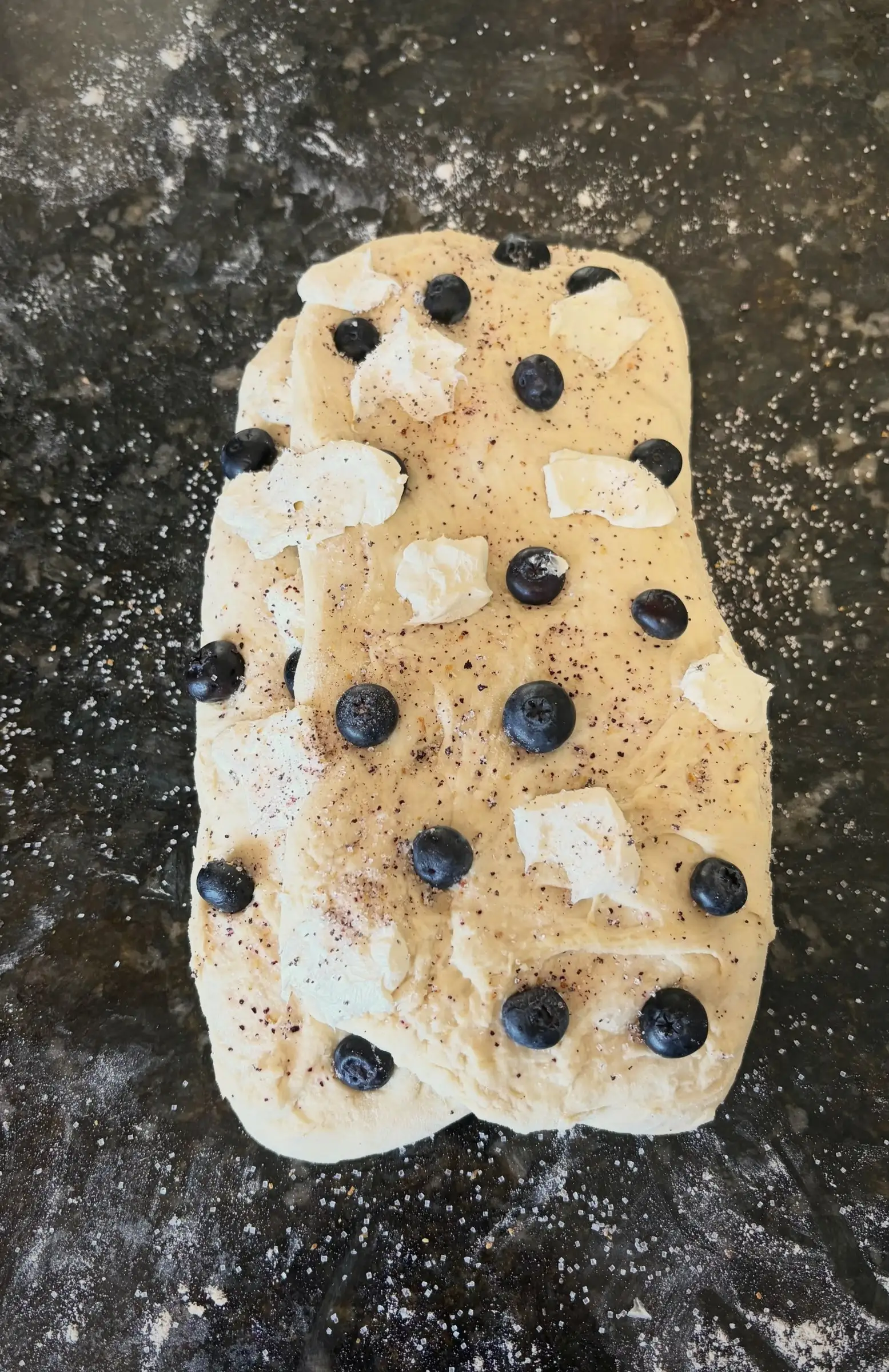 Shaped dough dotted with blueberries and cream cheese