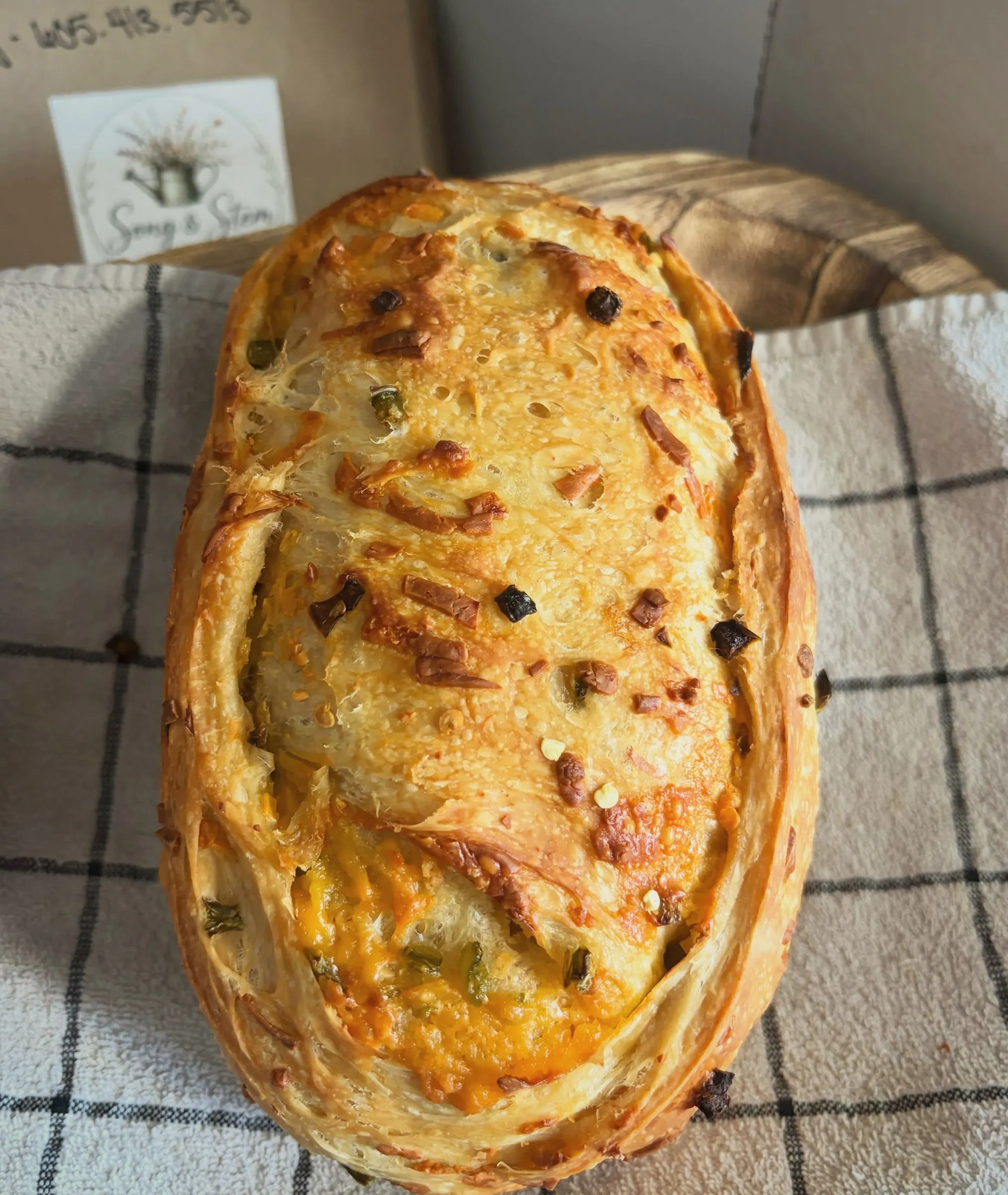 A jalapeño cheddar sourdough loaf on a checked towel