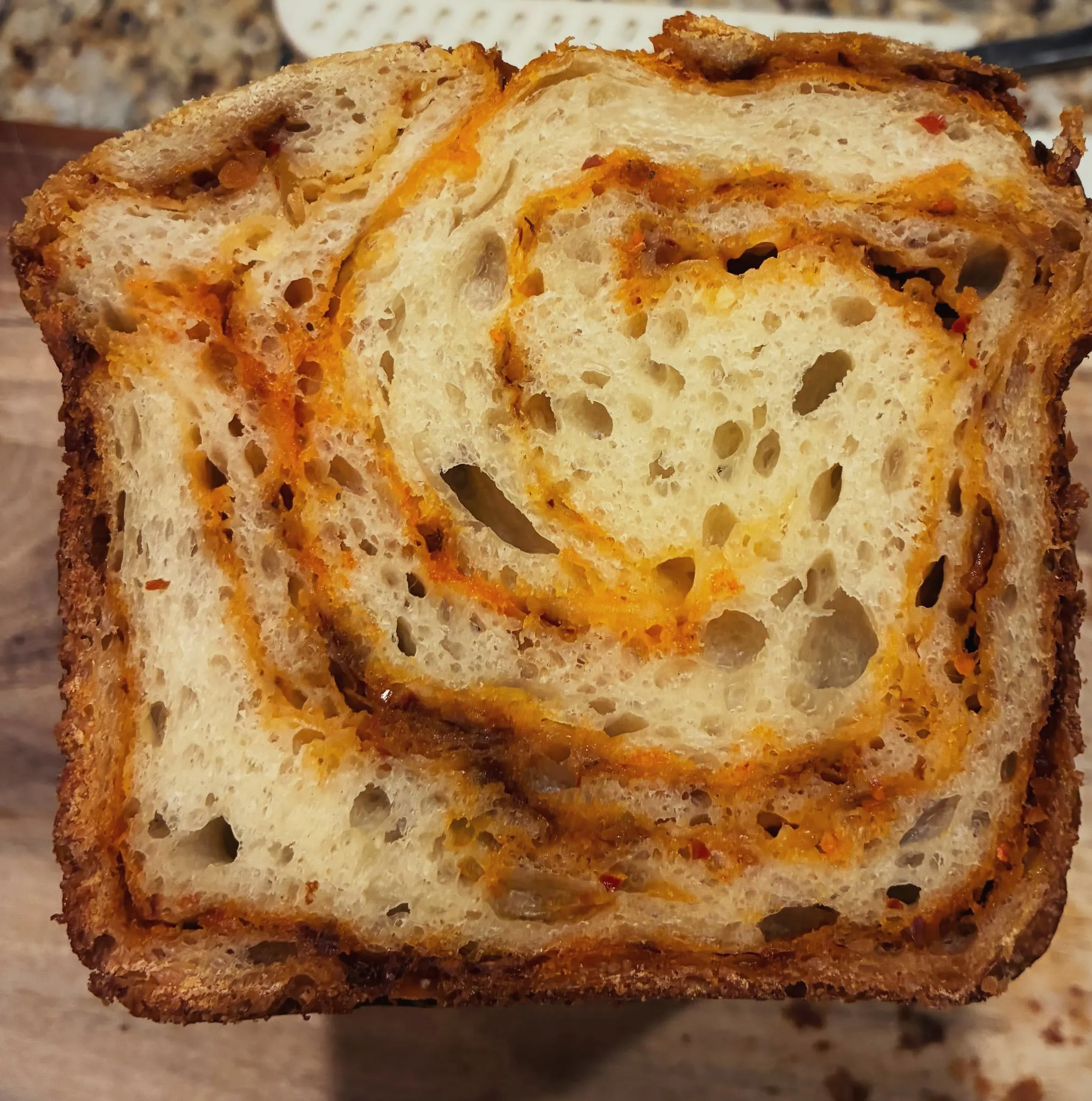 A slice of sourdough with a red chili oil and pepper jack swirl