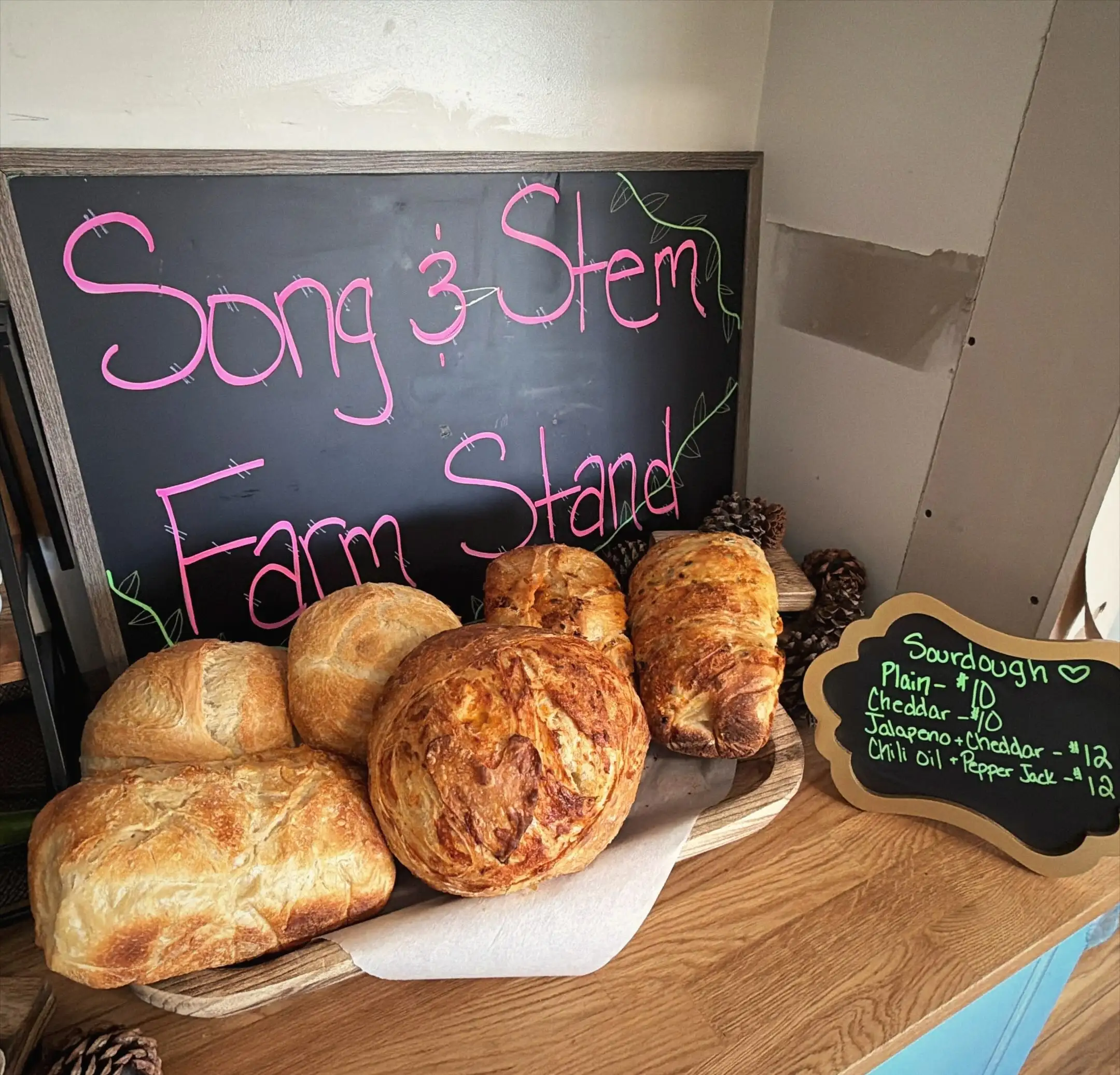 The Song & Stem Farm Stand chalkboard with fresh loaves